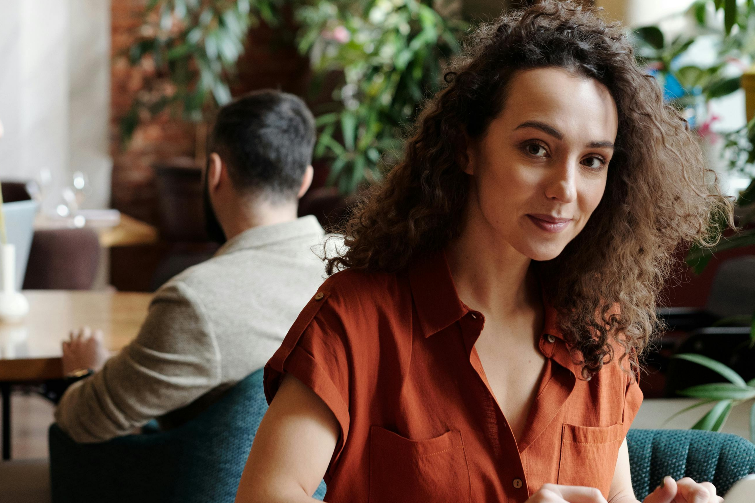 Une femme d'origine hispanique (trentaine) qui travaille sur son ordinateur dans un café moderne ou un coworking.